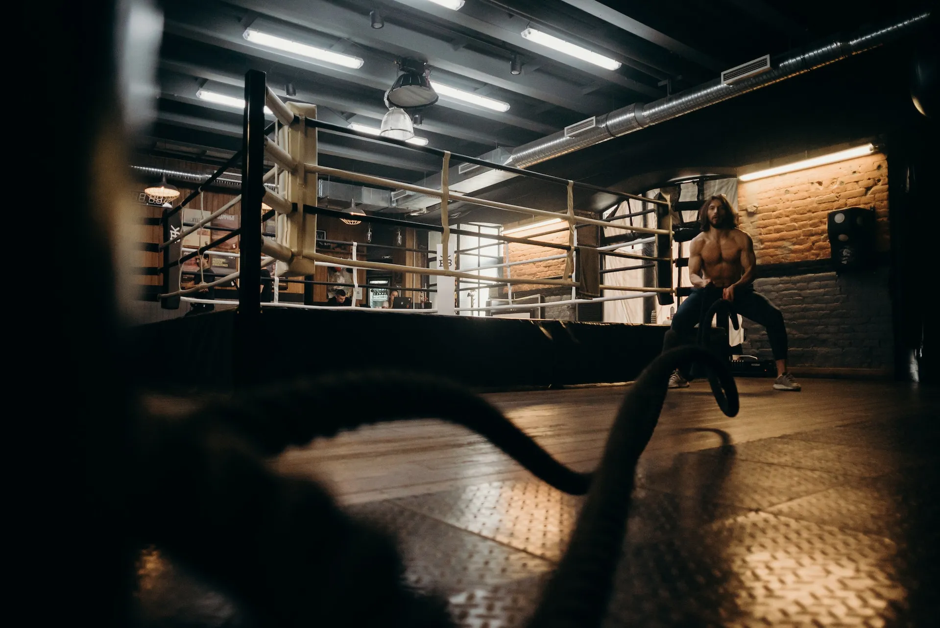 Athlete training with battle ropes in a dimly lit gym